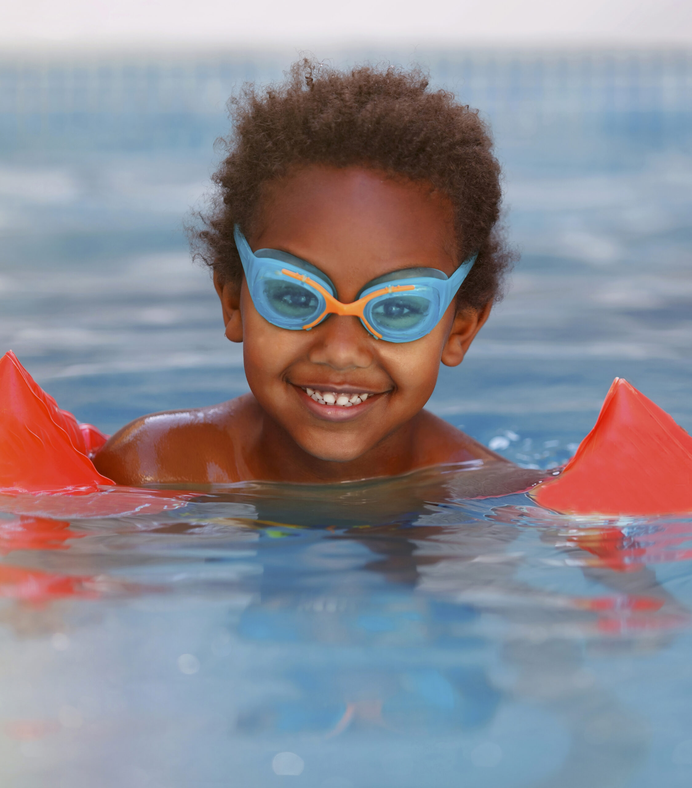 portrait d un garcon souriant nageant dans une piscine scaled