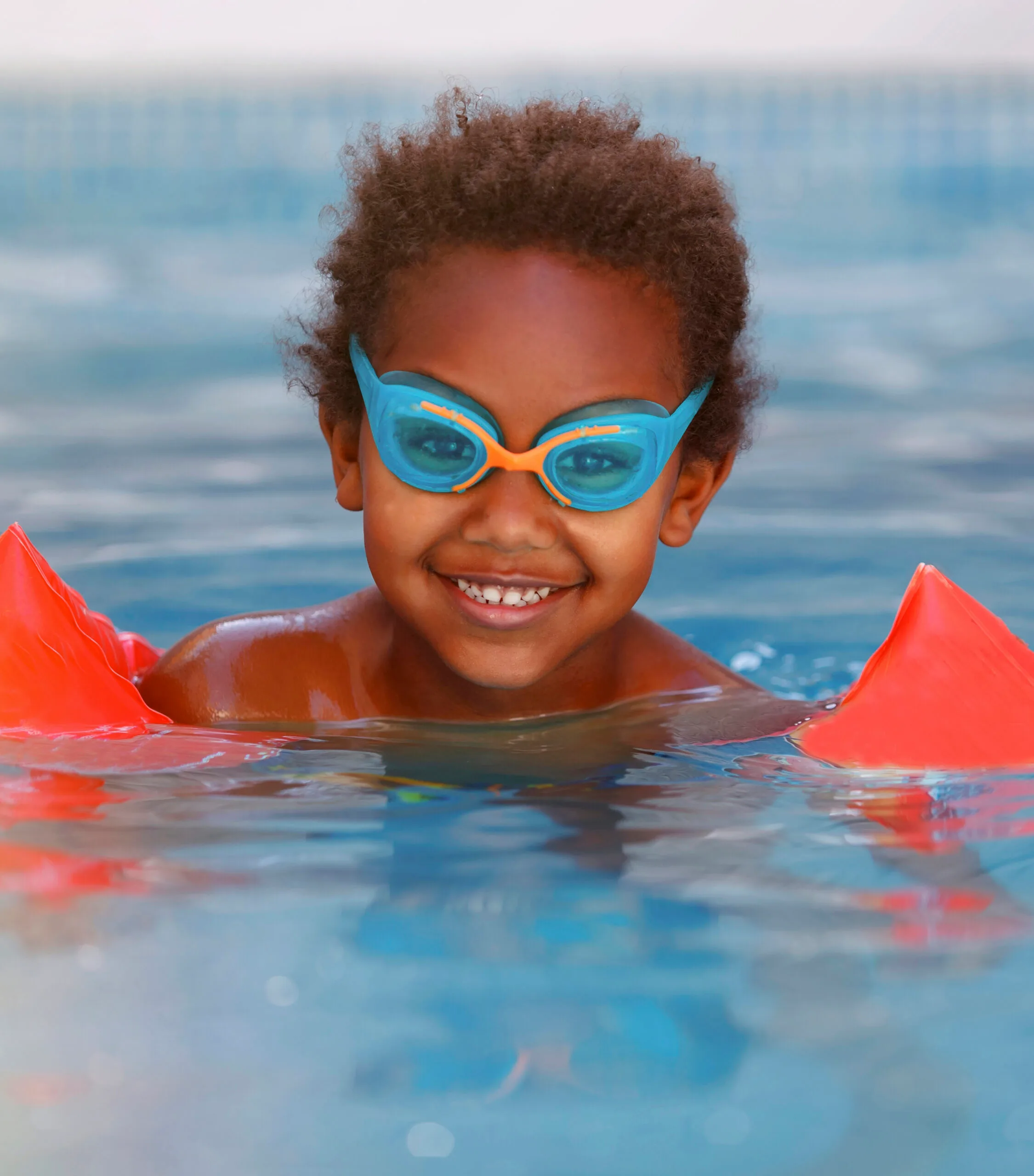 portrait d un garcon souriant nageant dans une piscine scaled